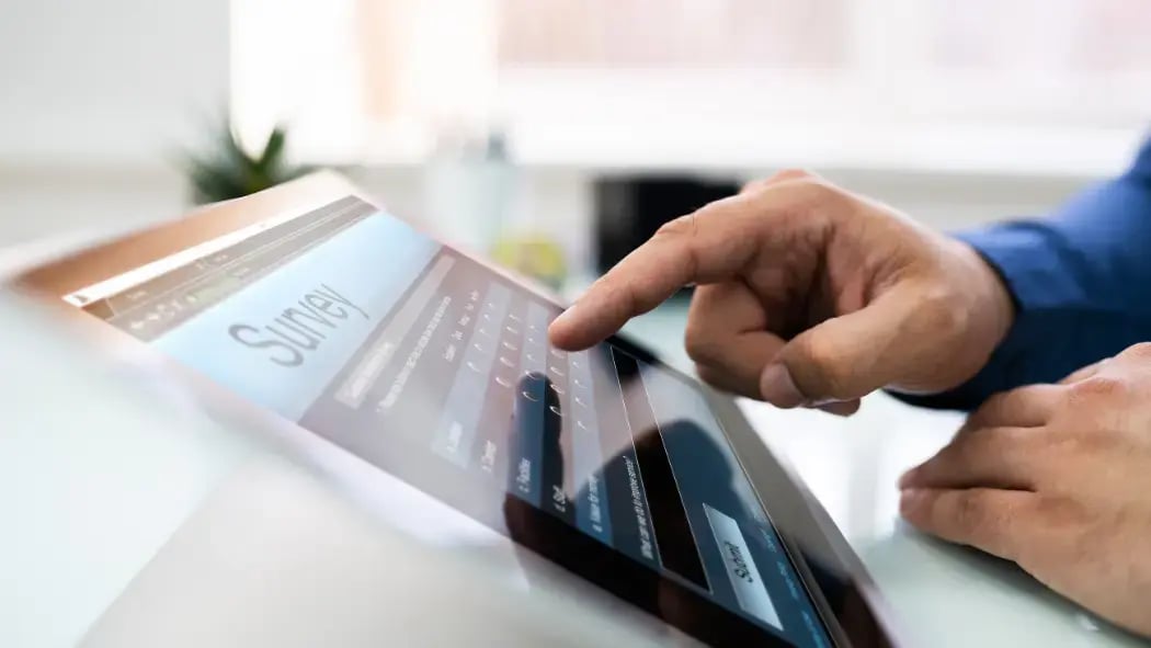 A hand hovering over an electronic tablet that is showing a survey on the screen