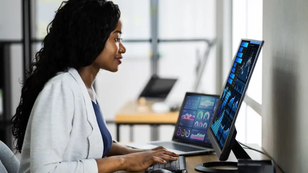 Woman sat at desk with data showing on the computer screen