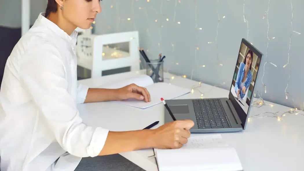 A woman sat at a laptop with somebody talking to her over a video call